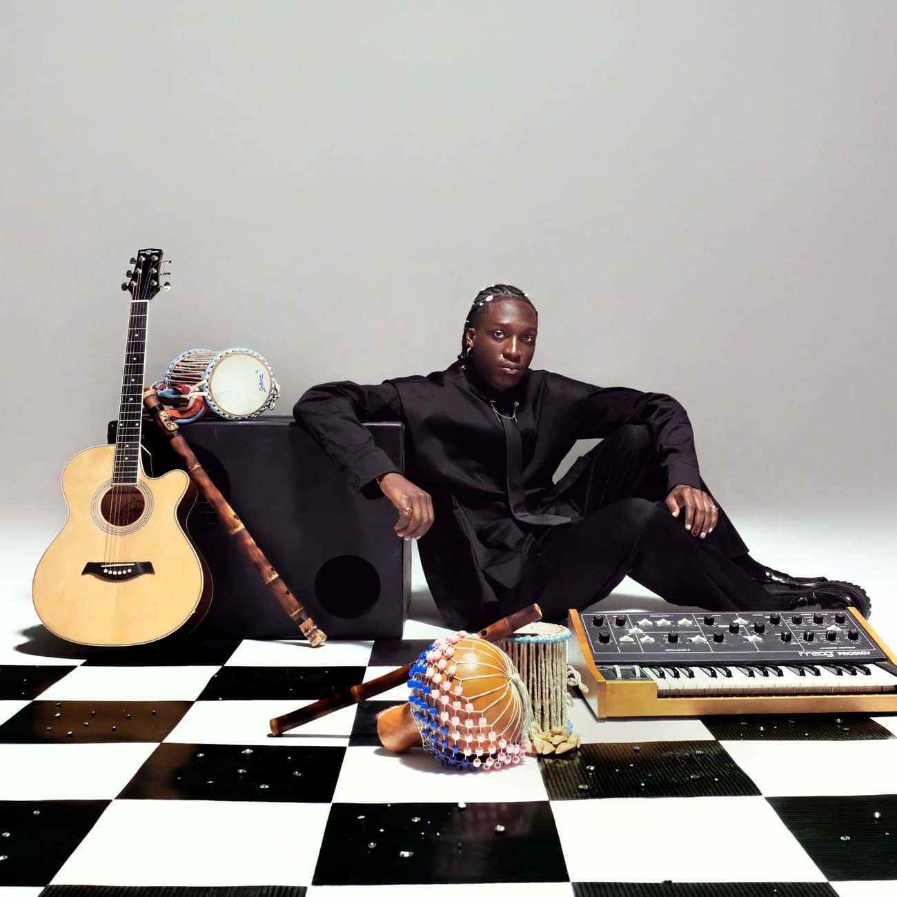 Musician seated among instruments on a checkerboard floor